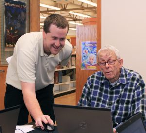image of volunteer helping elderly man with computer