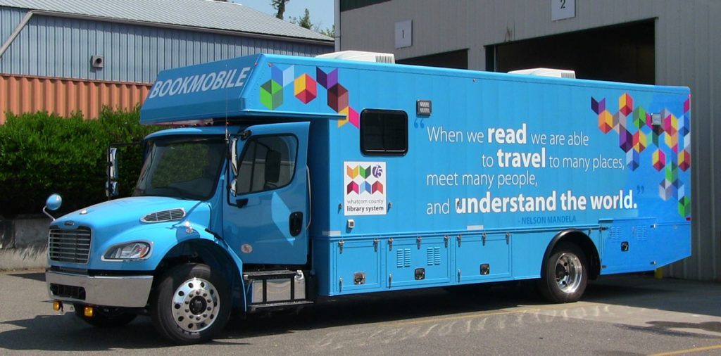 Photo of new bookmobile. Quotation painted on side: "When we read, we are able to travel to many places, meet many people, and understand the world." Nelson Mandela