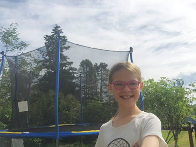 young girl with glasses in front of trampoline