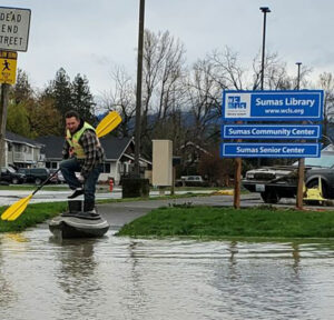 Paul Fullner riding a kayak to the flooded Sumas Library
