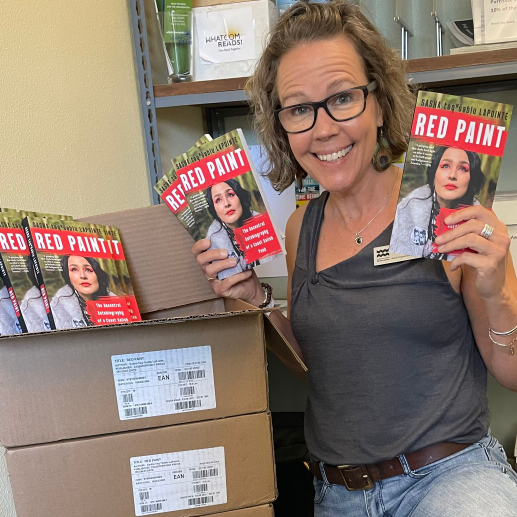 Claire McElroy holding copies of the book Red Paint by Sasha LaPointe