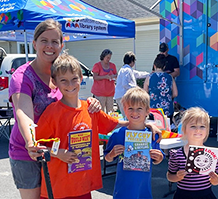 adult and three kids with books by bookmobile in Sumas