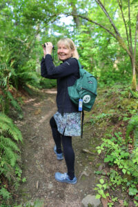 woman on hiking trail with Discover WA backpack and binoculars