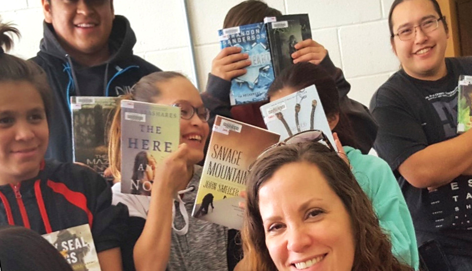 young people holding books and smiling