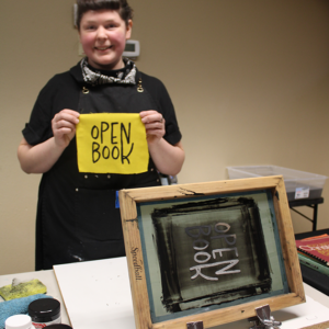 Woman silkscreening "Open Book" print on yellow fabric
