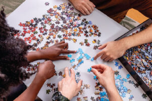 six hands working on a jigsaw puzzle