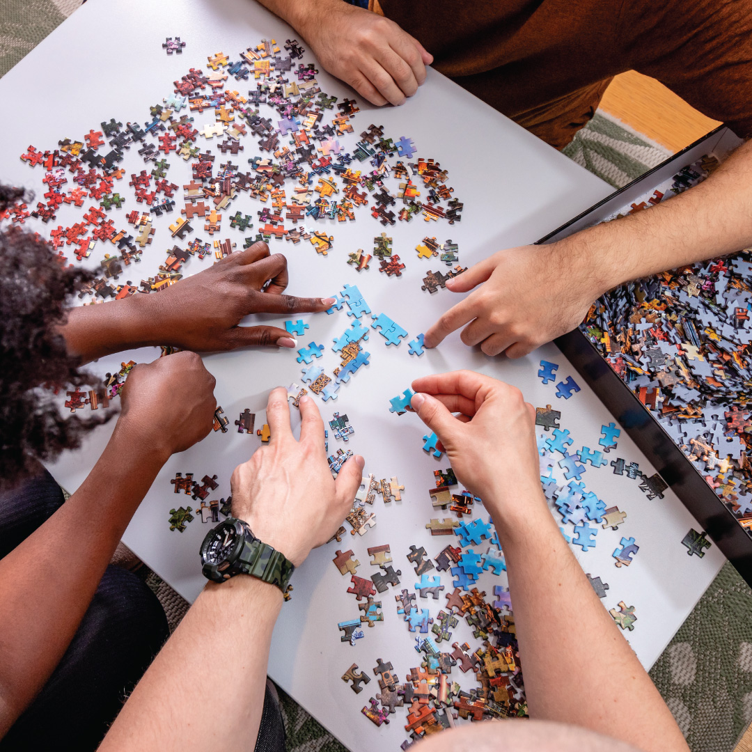 several hands working on jigsaw puzzle together